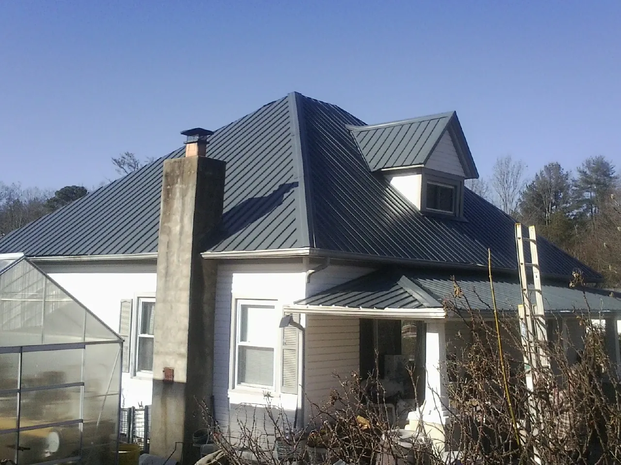 Dark blue standing seam metal roof on a white farmhouse with dormer — Slate & Tile Roof Repair by Roofing Brothers in Fort Wayne