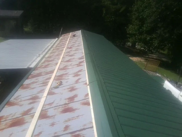 Old rusted panels beside newly installed green metal roofing — Wind Damage Roof Repair by Roofing Brothers in Fort Wayne