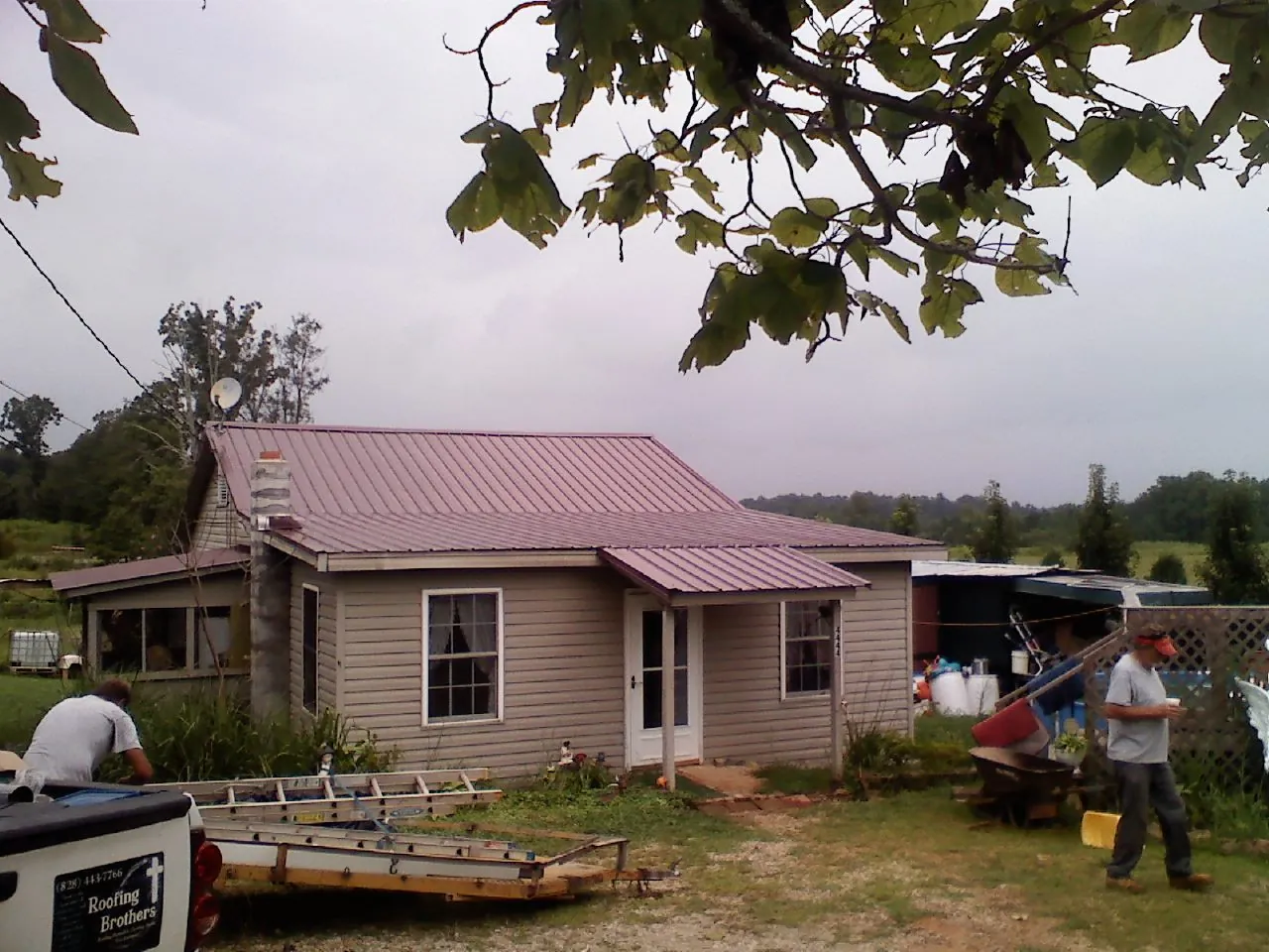 Crew finishing a mauve metal roof on a small farmhouse in Fort Wayne
