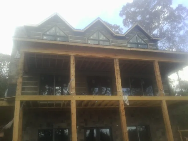 Dormers and porch framing on a large log home under construction — Roof Coating work by our crew in Fort Wayne