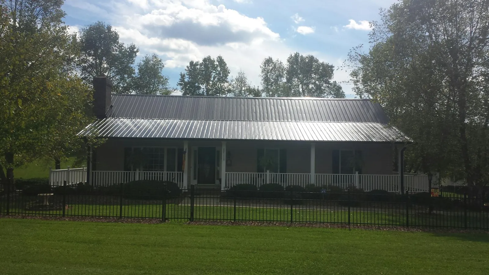 Gray metal roof on a brick ranch with a full width front porch — Gutter Guard Installation work by our crew in Fort Wayne